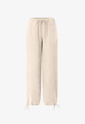 Világos bézs, bőszárú nadrág rugalmas derékpánttal és deréknál és bokánál húzózsinórokkal, puha anyagból készült.