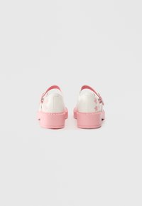 White shoes with pink accents, featuring a textured rubber sole, floral embroidery on the heels, and a smooth, shiny upper material.
