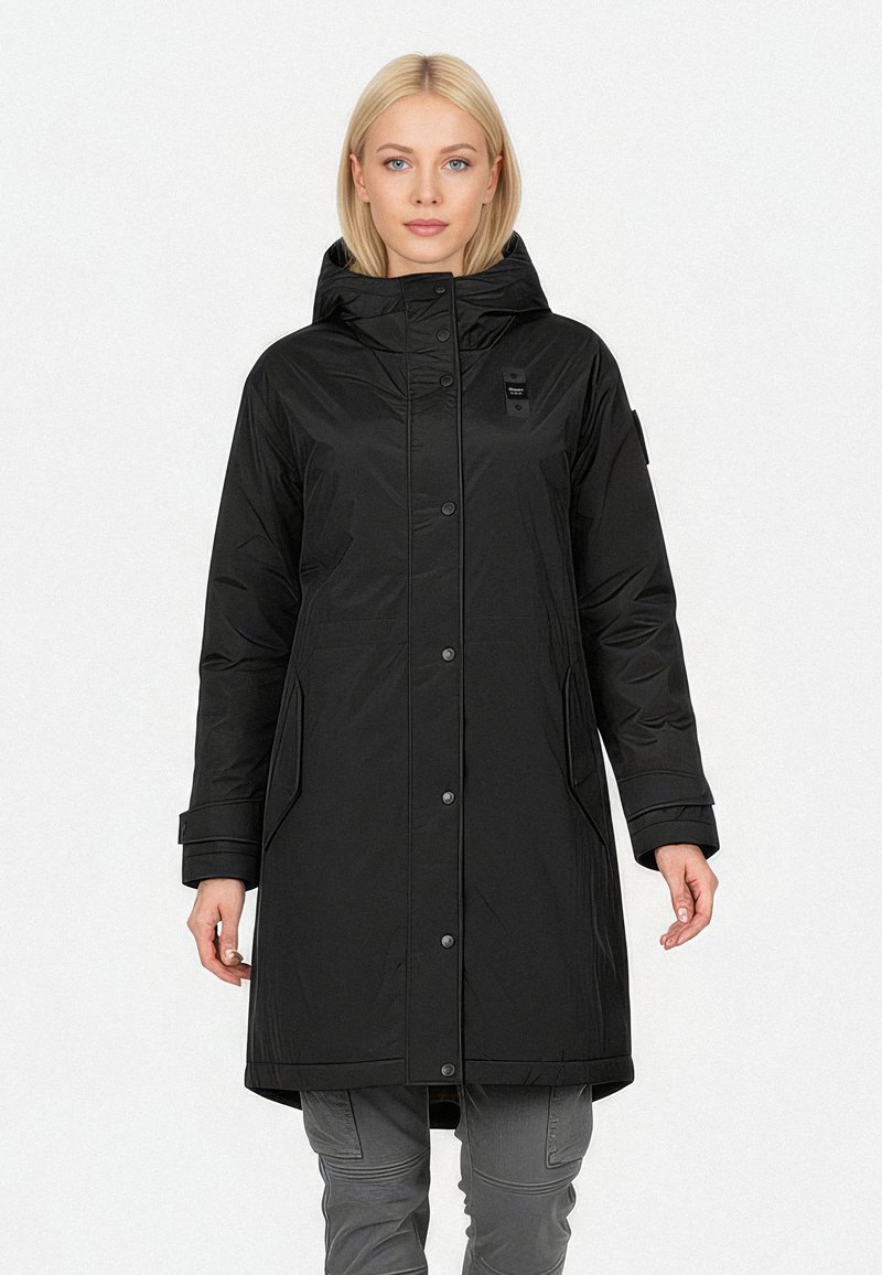 Sort lang frakke med hætte, lavet af skinnende materiale. Den har en frontlukning med trykknapper, sidelommer og et lille logo på brystet.