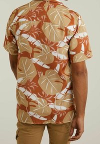 Camicia a maniche corte con un motivo di foglie marroni e beige. Realizzata in tessuto leggero con una vestibilità comoda e colletto a punte.