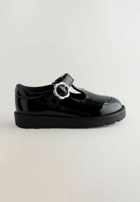 Chaussure en cuir verni noir avec un bout arrondi, design à sangle en T et accent en boucle circulaire argentée. Semelle épaisse en caoutchouc noir.