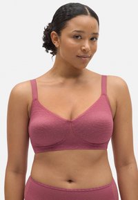 Sujetaubre mauve con textura de puntos, diseño sin aros, tirantes ajustables y forma triangular. Presenta copas sin costuras y tela suave.