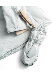 Hellgraue wasserdichte Jacke mit beigen Fleecebündchen und passenden grauen Handschuhen. Die Jacke verfügt über einen schmalen Handgelenkgurt mit einer Schnalle.