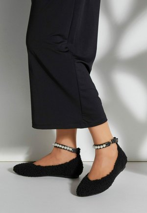 Ballerines noires texturées avec un extérieur duveteux et un design à bout pointu. Elles disposent d'une sangle de cheville accentuée de perles avec une boucle.