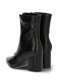 Botas de tobillo de cuero negro con punta afilada, textura suave y un tacón grueso. Presentan costuras curvas y un diseño superior sin costuras.