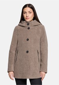 Bruine fleece jas met capuchon, met een gestructureerde buitenkant, zwarte knopen en zijzakken. Het ontwerp heeft een losse pasvorm voor comfort.