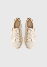 Sneaker beige con tomaia in pelle liscia, dettagli dorati e un accento a stampa leopardata sul tallone. Presentano lacci e zip laterale.