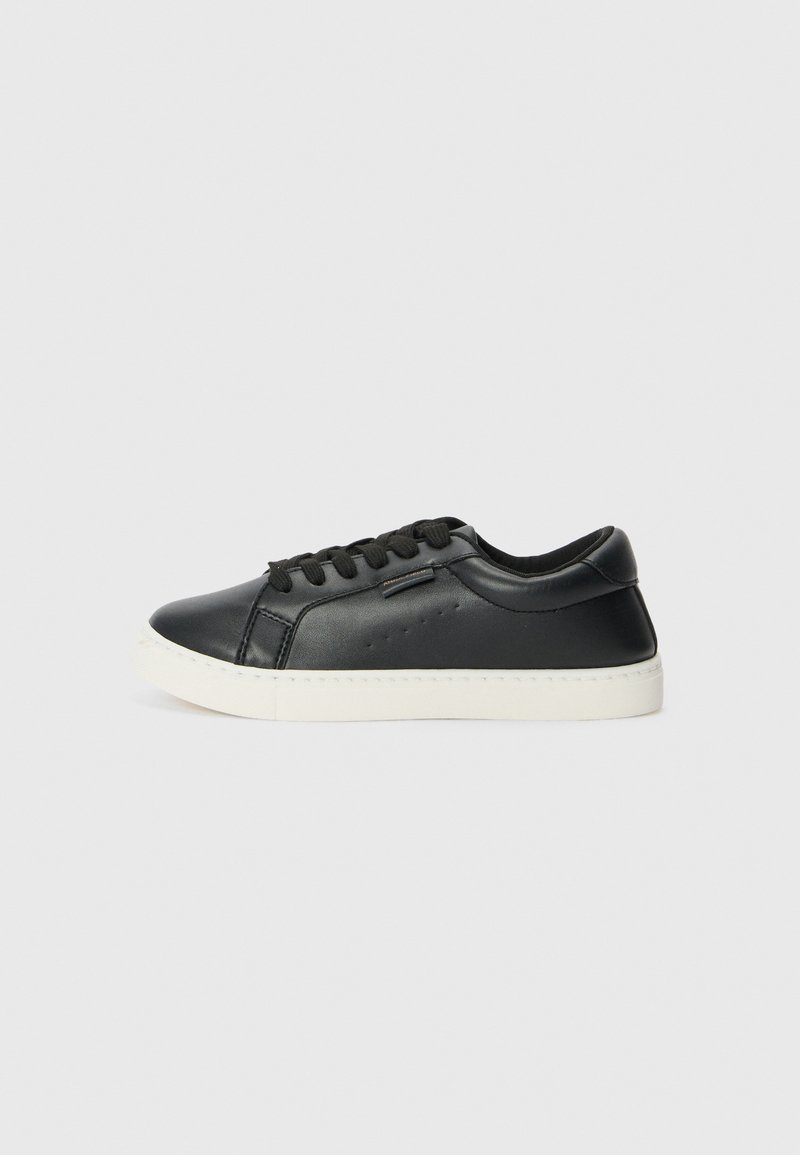 Svarte lærersneakers med rund tå, flat hvit gummisåle og svarte snøringer. Har subtile stikking detaljer på siden.