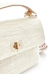 Beige woven fabric handbag with a rectangular gold twist-lock clasp and a leather handle attached by gold rings.