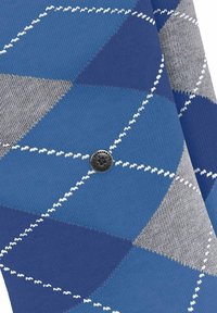 Tissu en tricot argyle bleu et gris avec des motifs en losange et des accents blancs. Un logo circulaire noir est placé au centre.