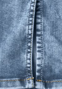 Helle blaue Denim-Stoff mit sichtbarer Textur, mit einem Reißverschluss und kontrastierenden gelben Nähten entlang der Kanten.