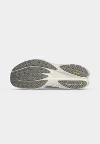 Semelle d'une chaussure de course avec motifs de la bande de roulement gris, semelle intermédiaire blanche, et logo Puma jaune ainsi que texte PUMAGRIP sur fond gris clair.