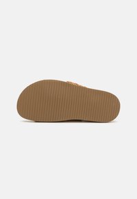 Brown rubber sole with horizontal grooves for traction, featuring a textured finish and a rounded toe shape.