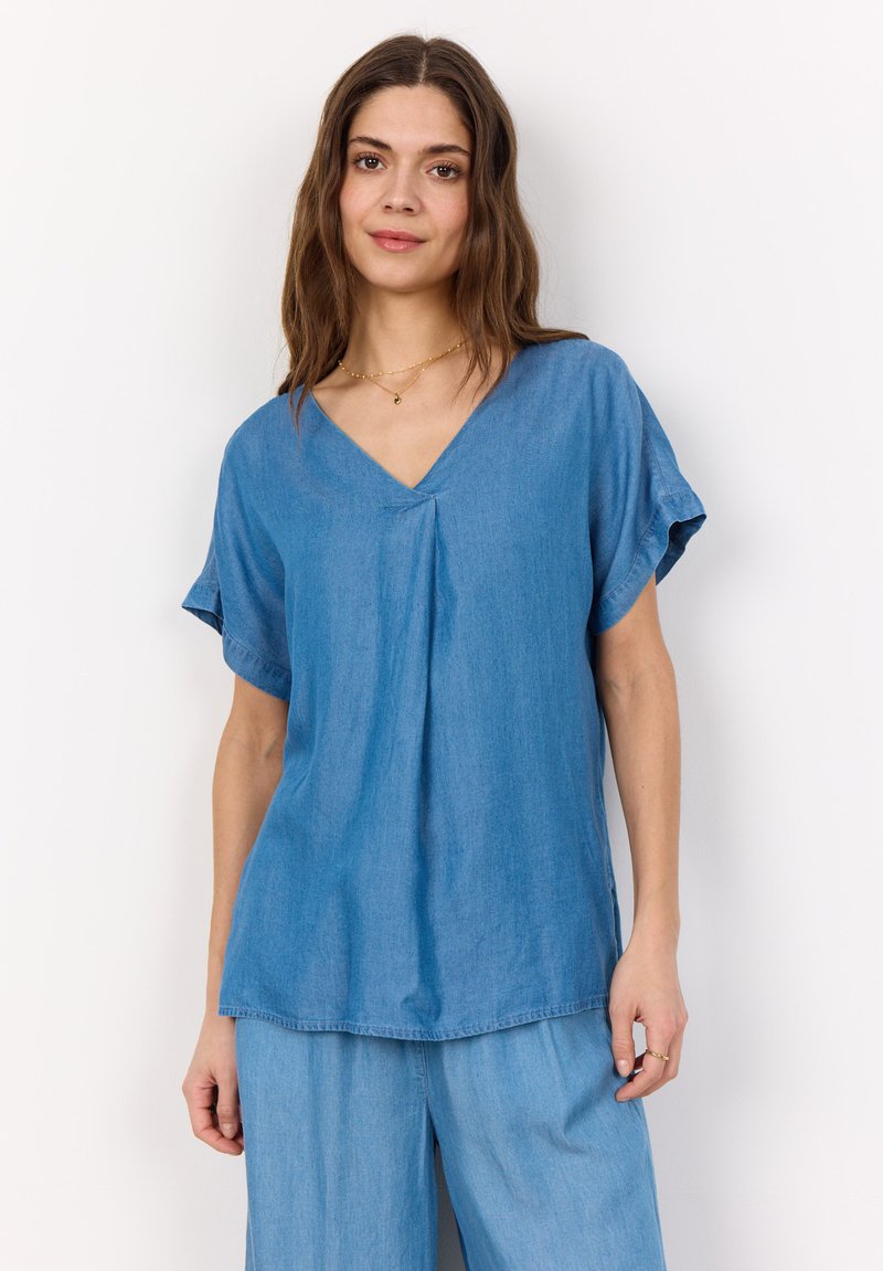 Light blue, V-neck, short-sleeve top made of soft fabric, featuring subtle pleats and a relaxed fit, paired with matching loose trousers.