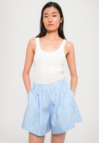 Hvit ribbet tank topp og blåstripete høyt midje shorts med legg og lommer. Smooth tekstur, uformelt design, avslappet passform.