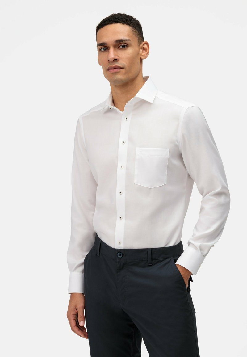 Witte lange mouwen shirt van lichtgewicht stof, met een borstzak, knoopsluiting en een klassieke kraag, gecombineerd met donkere broek.