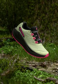 Αθλητικό παπούτσι ανοιχτό πράσινο με μαύρες λεπτομέρειες, ροζ αποχρώσεις και υφή στο επάνω μέρος. Διαθέτει μαλακή σόλα και αδιάβροχο υλικό Gore-Tex.
