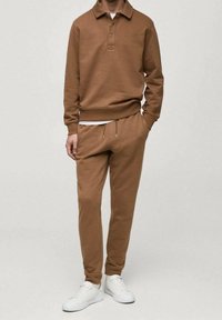 Brauner Baumwollpullover mit Kragen und drei-Knopf-Blende, kombiniert mit passenden Jogginghosen mit elastischem Bund und Kordelzug.
