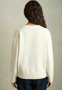 Maglione color crema con orlo e polsini a costine, caratterizzato da una vestibilità ampia e maniche raglan, realizzato in materiale morbido.