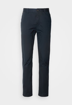 Chino léger navy avec une coupe droite, fermeture à boutons, passants de ceinture et un fini subtil. Dispose de poches classiques et de détails de couture minimalistes.