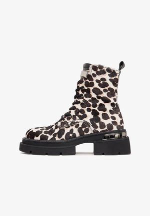 Fekete-fehér leopárdmintás bokacsizma prémből, masszív fekete talppal és ezüst színű fém díszítéssel a bokán.