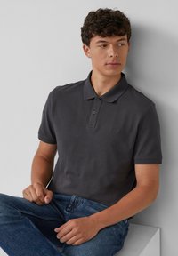 Donkergrijze polo met gestructureerde stof, een klassieke kraag, twee knopen en korte mouwen, gecombineerd met blauwe spijkerbroeken.