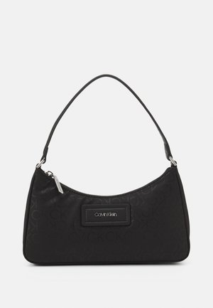 Czarna torba na ramię Calvin Klein z subtelnym wytłaczanym wzorem logo, srebrnym zamkiem i pojedynczym zakrzywionym paskiem.