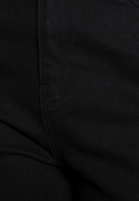 Černé džíny s hladkou texturou, rovný střih a výrazné švy podél švů. Obsahuje detail boční kapsy.