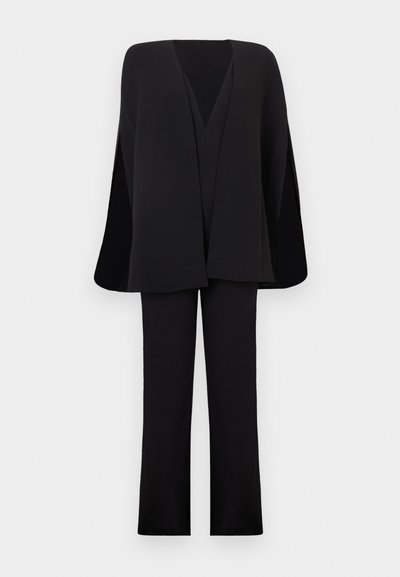 Mustad laiad püksid, mille juurde kuulub sobiv üle suurusega V-kaelusega mantel mantel laiade varrukatega, esitletud tavalise valge tausta peal.