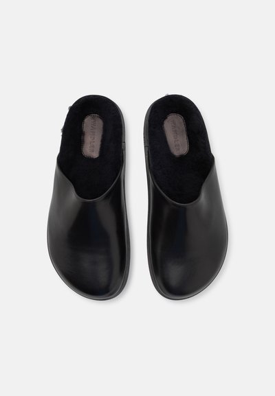 Fekete bőr clogs sima felülettel és kerek orral. Puha fekete bélés belül. Nincs látható fémalkatrész vagy minta. Egyszerű design.