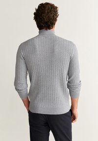Jersey gris de punto con un patrón acanalado texturizado, cuello alto y mangas largas con puños enrollados. Tejido ligero.