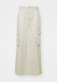Beige cargo-housut, joissa on leveät lahkeet, valmistettu puuvillasta. Ominaisuuksiin kuuluu kaksi suurta etutaskua ja kaksi sivutaskua, ja vyötäröllä on napitus.