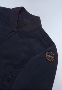 Ναυτική bomber jacket με ριγωτό γιακά, κλείσιμο με φερμουάρ, πλαϊνή τσέπη και στρογγυλή ένδειξη λογότυπου στον ώμο. Απαλή υφή και ελαφρύ σχέδιο.