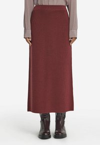 Stickad bordeaux maxi kjol med ett åtsittande midjeband, strukturerad tyg och rak silhuett, kombinerad med svarta ankelstövlar.
