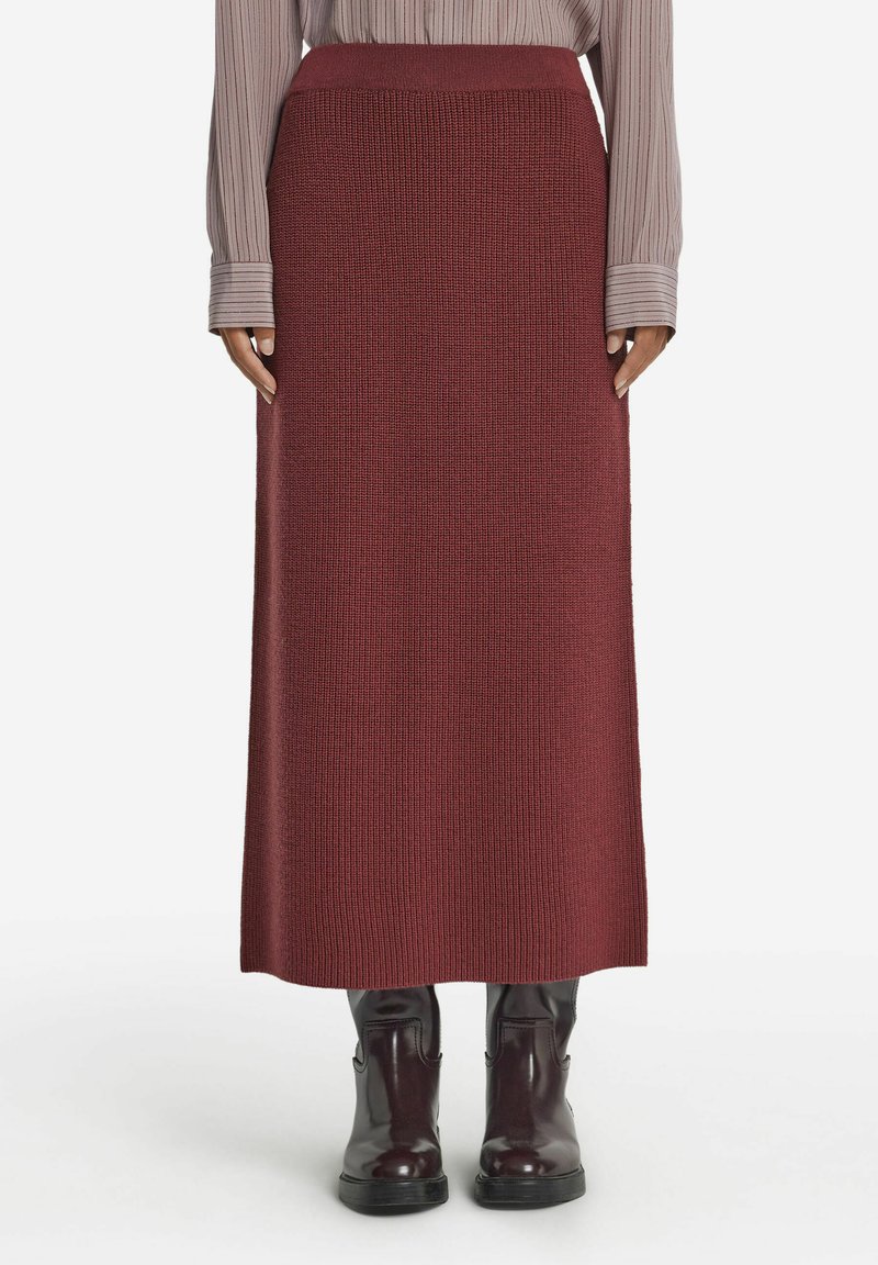 Stickad bordeaux maxi kjol med ett åtsittande midjeband, strukturerad tyg och rak silhuett, kombinerad med svarta ankelstövlar.