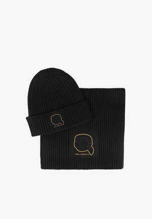 Black ribbed knit beanie and scarf set featuring gold logo of a stylized face on both items. Soft texture with a snug fit.