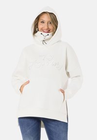 White hooded sweatshirt with a high collar, front pockets, and "Legendary" text in silver. Soft texture and relaxed fit.
