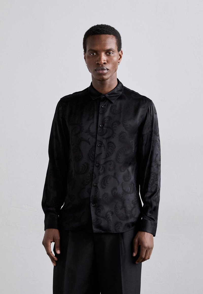 Camicia nera con bottoni, maniche lunghe, caratterizzata da un sottile motivo paisley, realizzata in tessuto morbido con colletto e bottoni frontali.