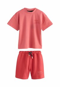 Koraalroze matching set met een t-shirt met korte mouwen en logo-print, en shorts met elastische taille en trekkoord. Zacht katoenmateriaal.