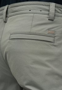 Ανοιχτό γκρι παντελόνι με ραφές, με πίσω τσέπη welt και ένα μικρό ορθογώνιο διακριτικό λογότυπο BOSS κοντά στην τσέπη.