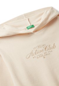Pískový žebrovaný svetr s kapucí a vyšitým nápisem "Active Club" a zelenou etiketou United Colors of Benetton na límci.