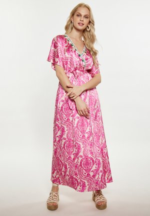 Rochie maxi roz cu un model paisley, cu mâneci scurte în evantai, decolteu în formă de V și o curea din material la talie. Sandale espadrile plate.