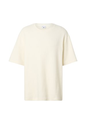 Roomkleurige, kortärmelig trui met ronde hals, gestructureerde stof, losse pasvorm en een subtiel, reliëflogo op de borst.