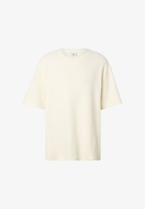 Krém színű, rövid ujjú, kerek nyakú, texturált kötött felső laza szabással és a mellkason finoman dombornyomott logóval.