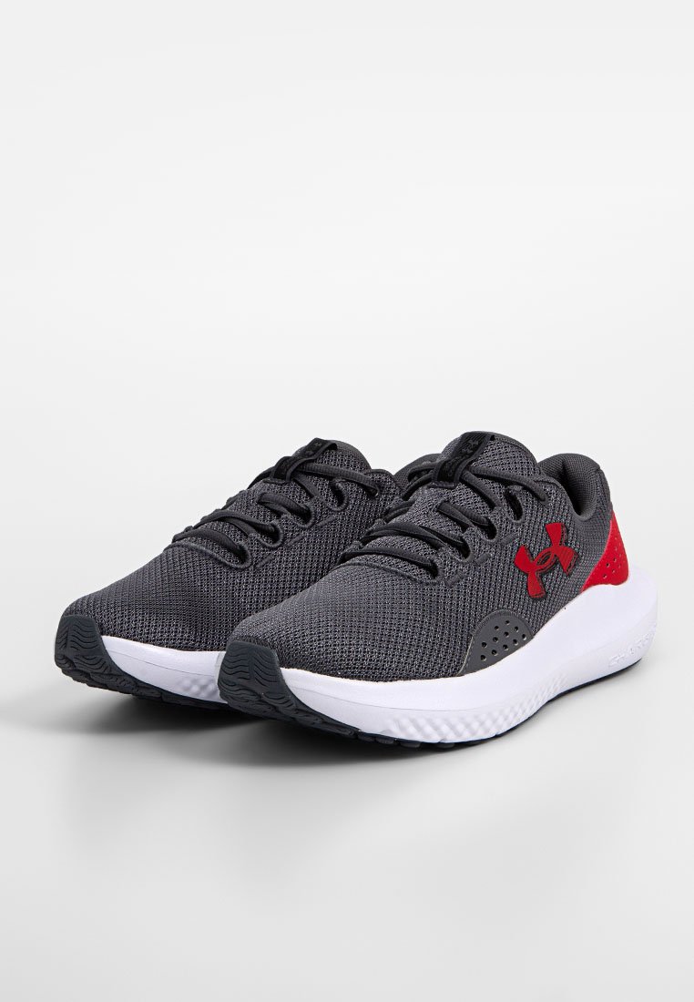 Zapatillas deportivas grises con una parte superior de malla texturizada, acentos rojos, diseño con cordones y una suela blanca que presenta un patrón de relieve.