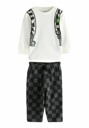 Camisa blanca de manga larga con tirantes gráficos y dibujos animados. Pantalones cortos a rayas negros y gris oscuro con cintura elástica.