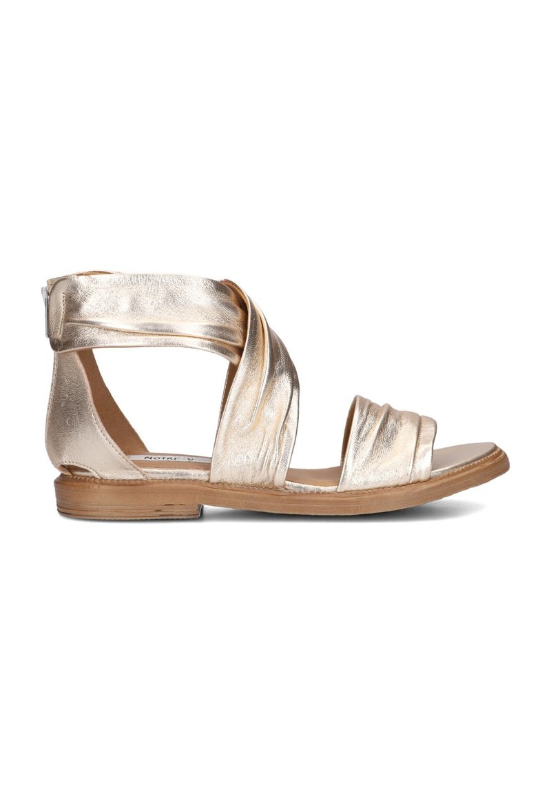 Metallische gouden platte sandals met een gedraaide bandontwerp, open teen en beige zool. Zachte textuur met een minimalistische stijl.