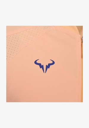 Top deportivo de color melocotón con detalles de malla, que cuenta con un logo azul. Textura suave con perforaciones sutiles para mayor transpirabilidad.