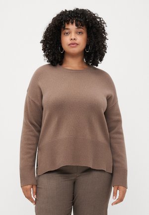 Brun ribbestrikket genser med rund hals, senkede skuldre og sideslitser i nederkanten. Kombinert med matchende brune bukser.