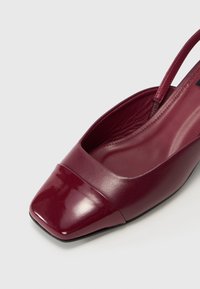 Sandal de couro bordô com salto baixo e ponta quadrada, acabamento brilhante. Apresenta um ligeiro salto e um forro interior suave.